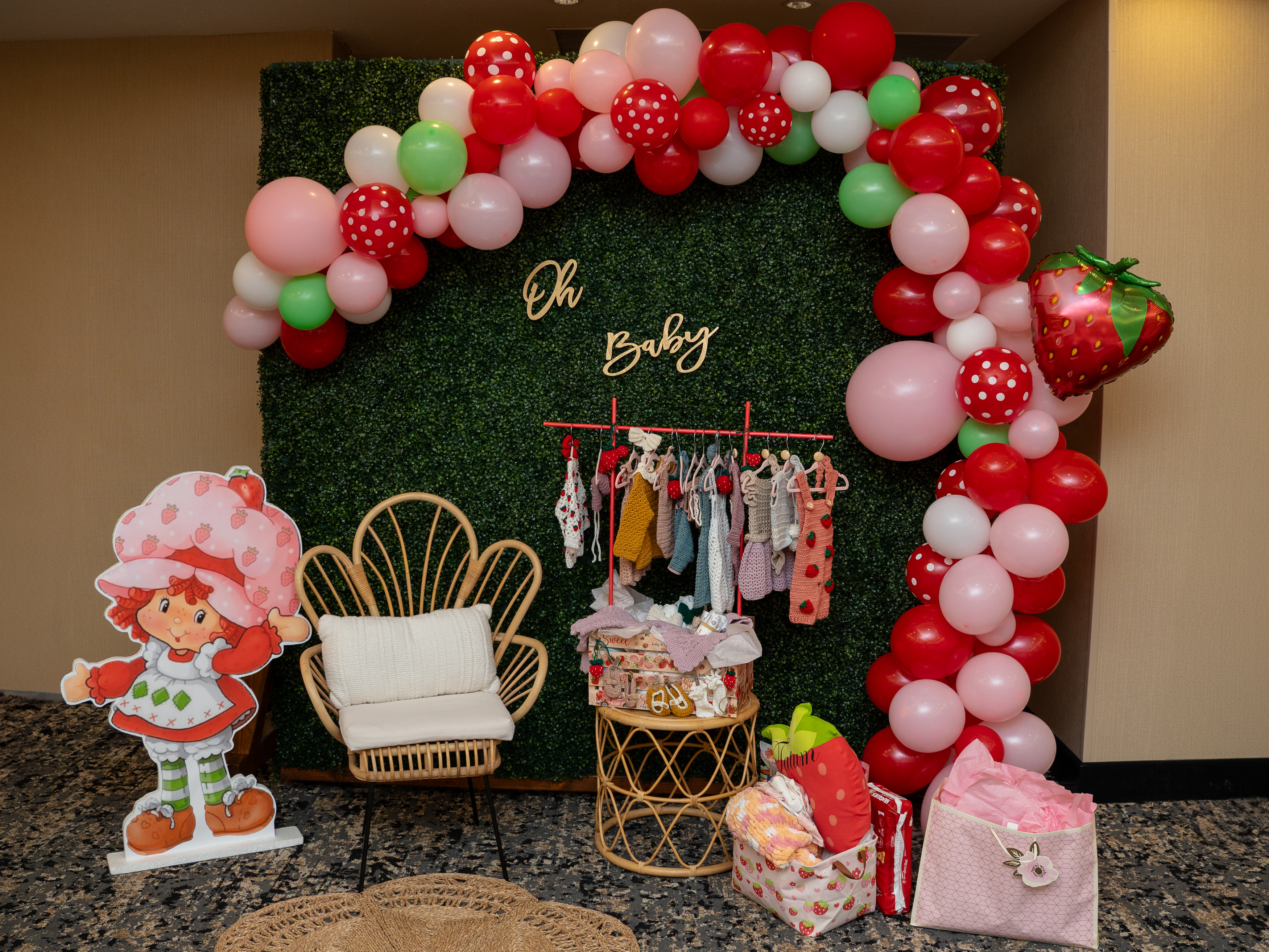 Baby shower decor featuring a chair and strawberry shortcake-themed decorations