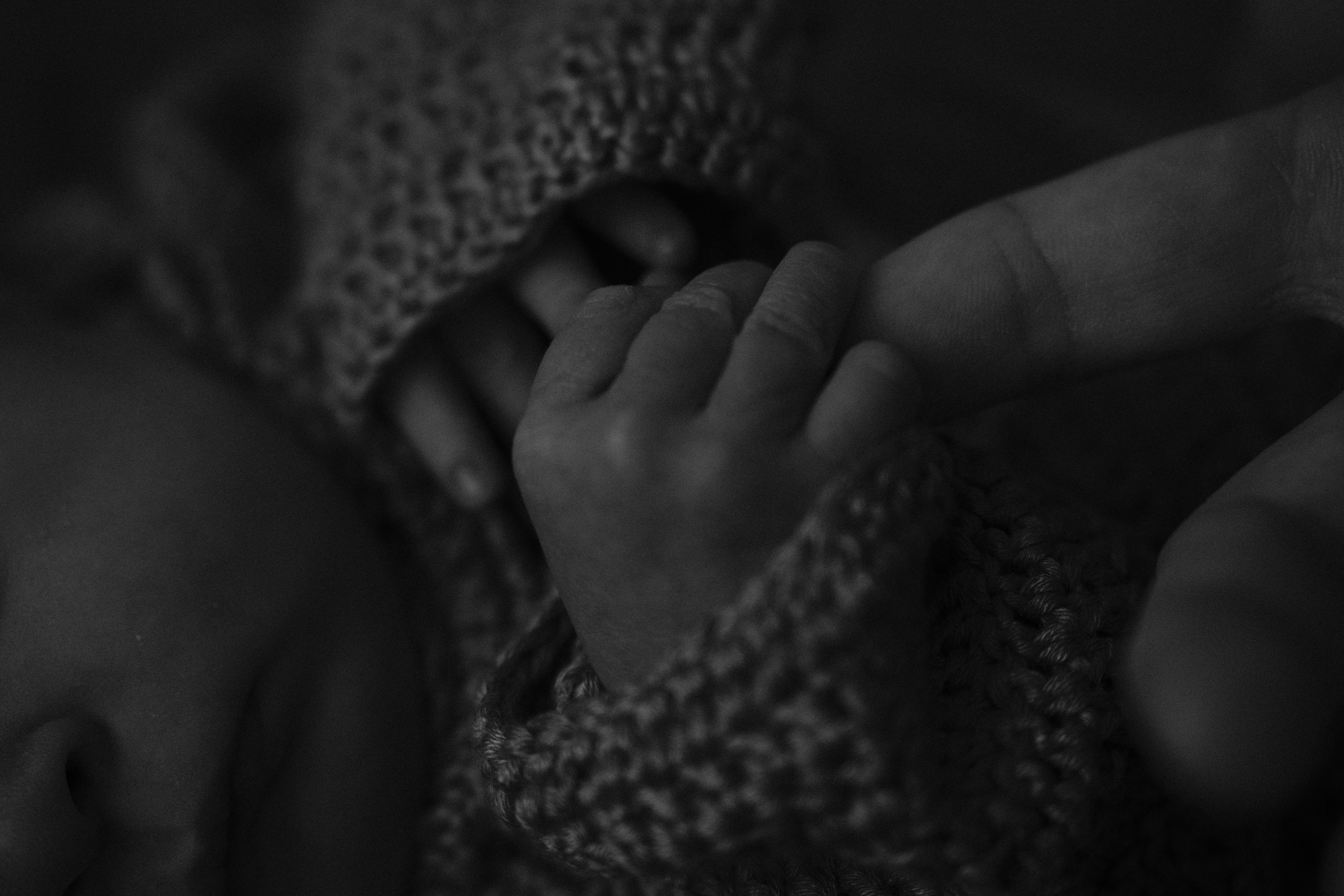 Baby holding their father’s finger during a family photo session