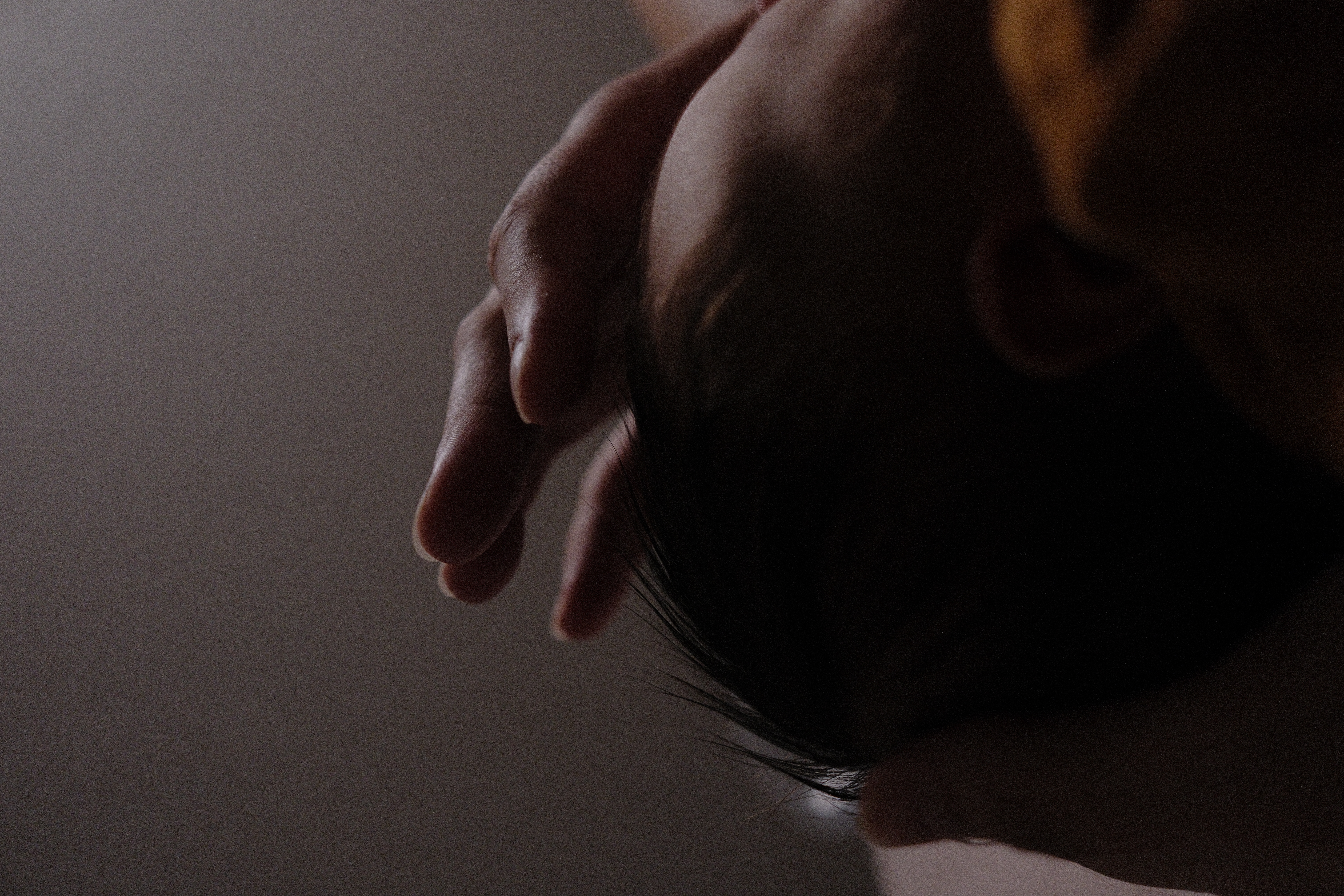 Mother holding her baby and gently touching the baby's head during a lifestyle photo session