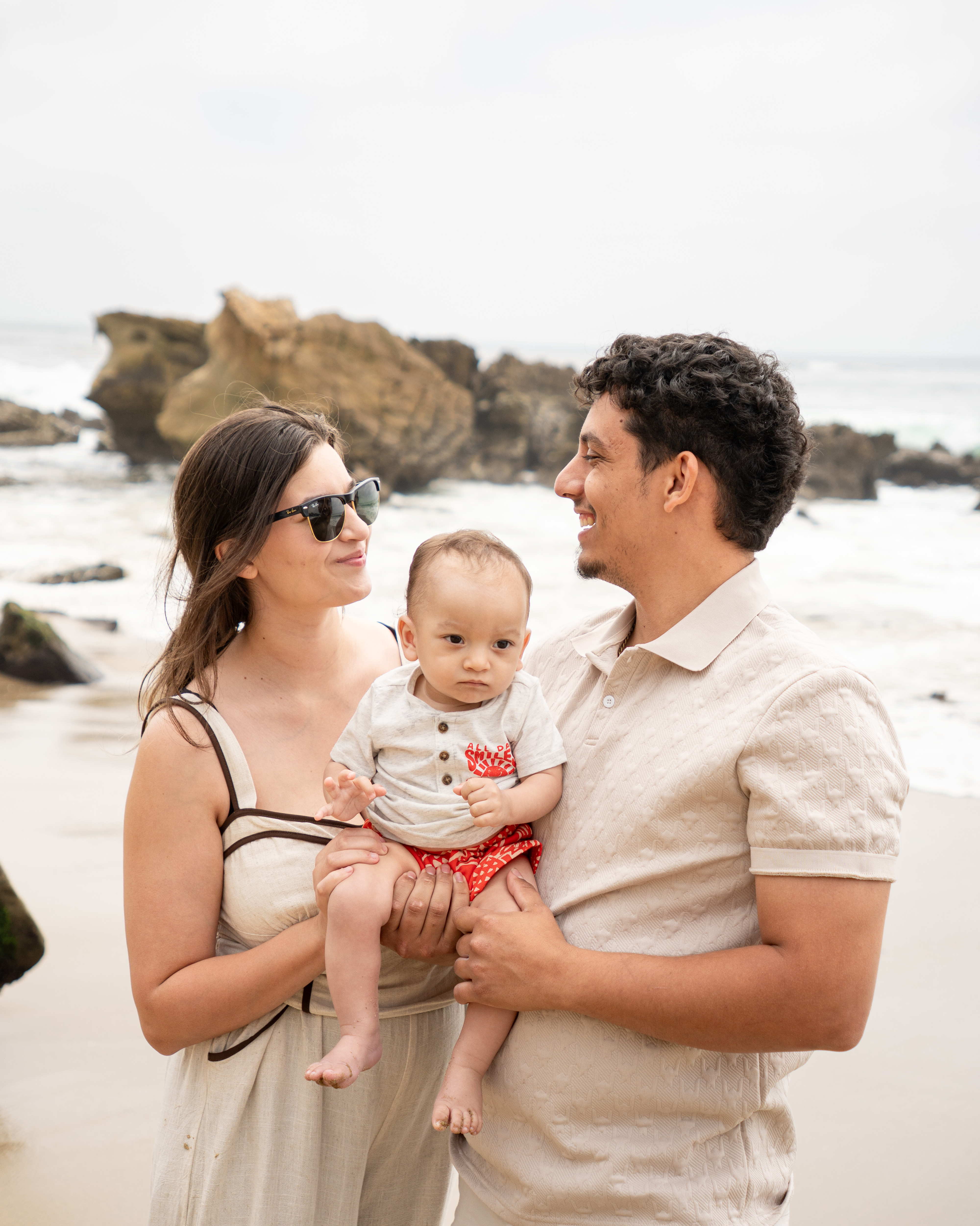 Family photo session at the beach with two adults and a baby