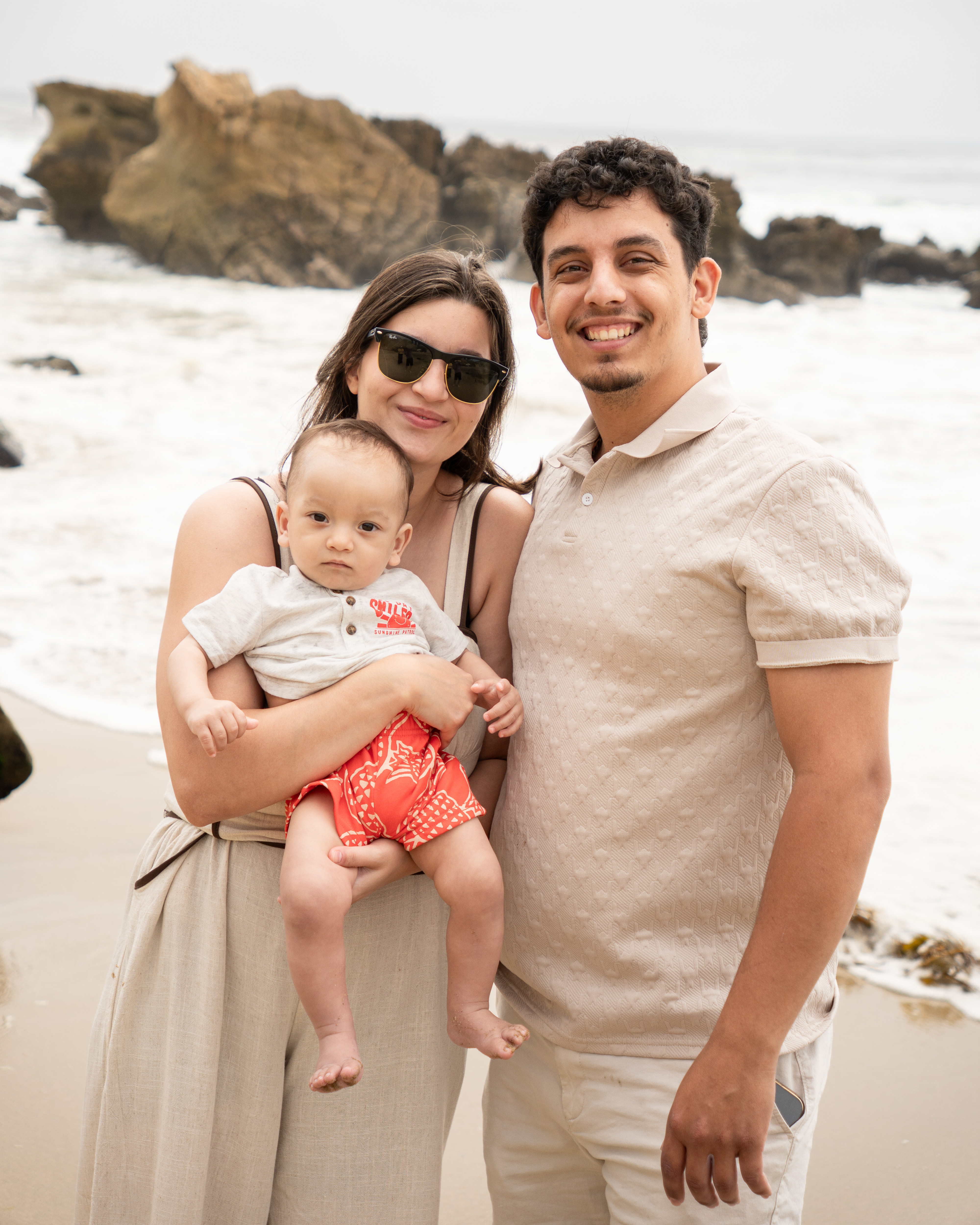 Family photo session on the beach with two parents and a baby